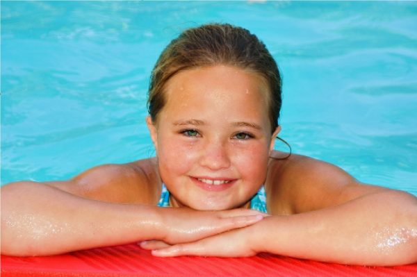 Menina nadando na piscina, feliz.